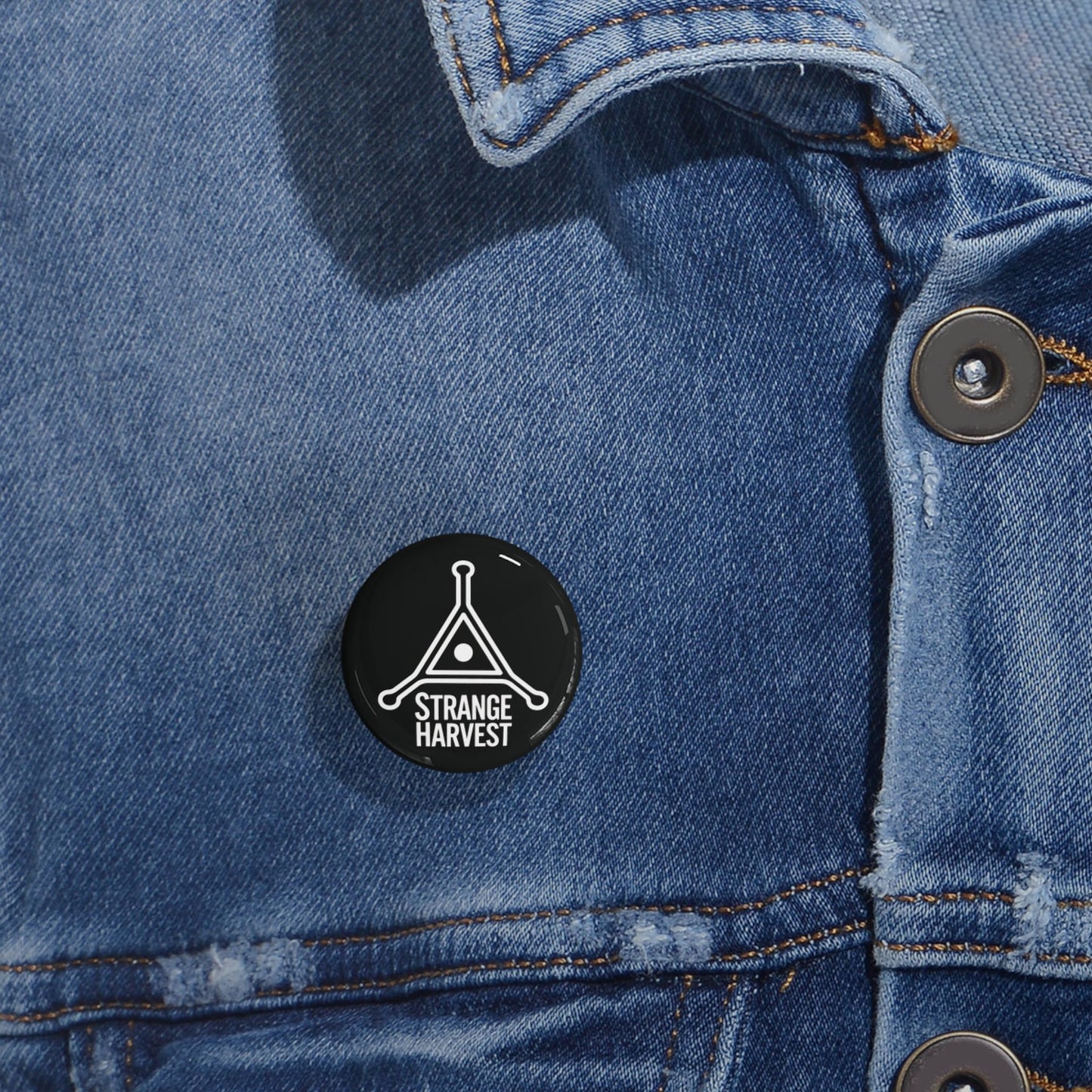Black 'Strange Harvest' pin on a blue denim jacket